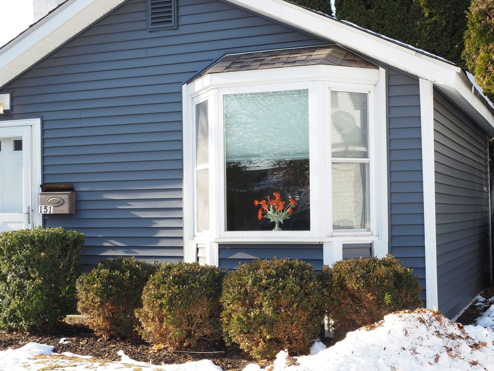 Cozy blue house with a bay window and snow in Doylestown, PA.
